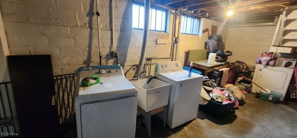 Laundry area with washer and clothes dryer and concrete block wall