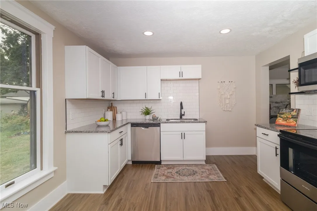Kitchen with stainless steel appliances, stone countertops, wood finished floors, plenty of natural light, and recessed lighting