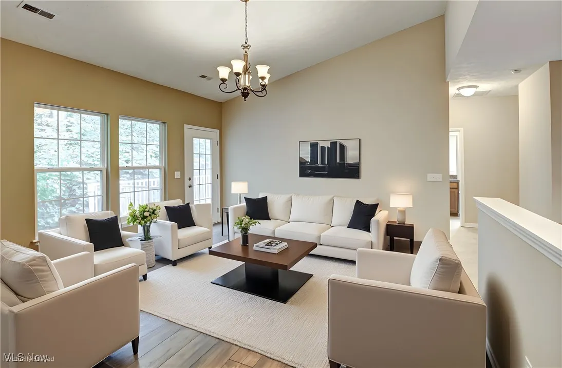 Living room featuring vaulted ceiling, a chandelier, and wood finished floors