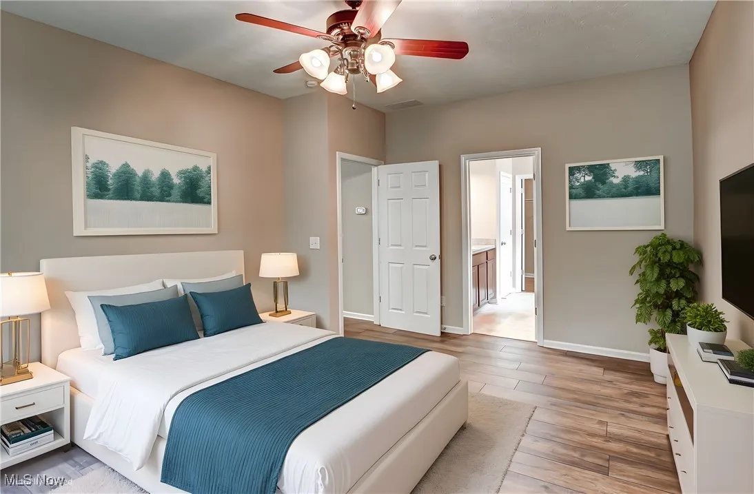 Bedroom with wood finished floors, a ceiling fan, and ensuite bathroom