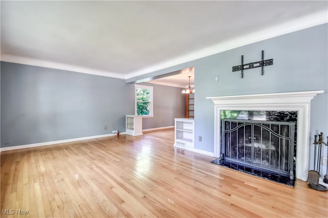 Unfurnished living room featuring wood finished floors, a chandelier, and a fireplace