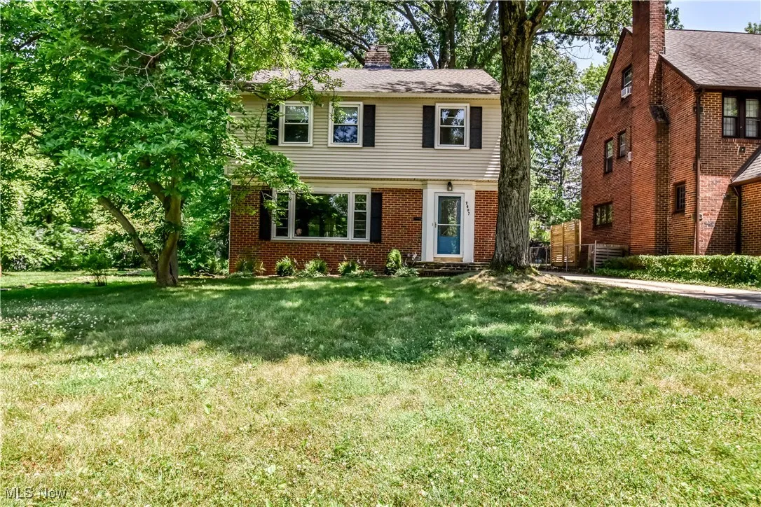 Colonial inspired home featuring a front yard, a chimney, and brick siding