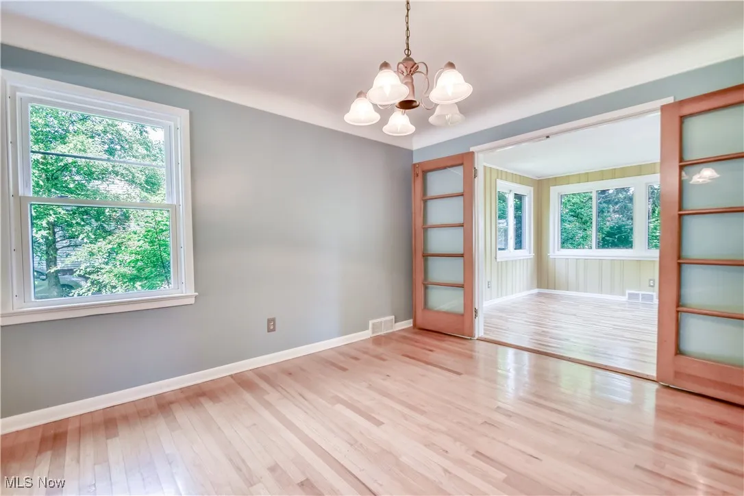 Empty room featuring a chandelier, healthy amount of natural light, and wood finished floors