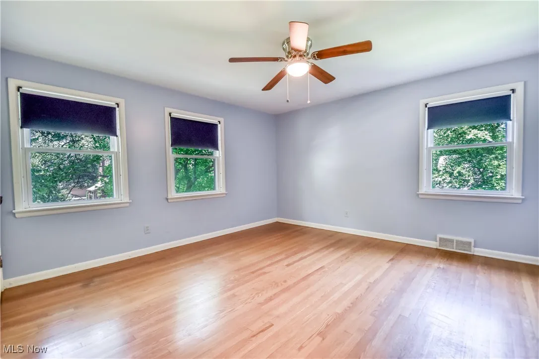 Unfurnished room with healthy amount of natural light, wood finished floors, and a ceiling fan