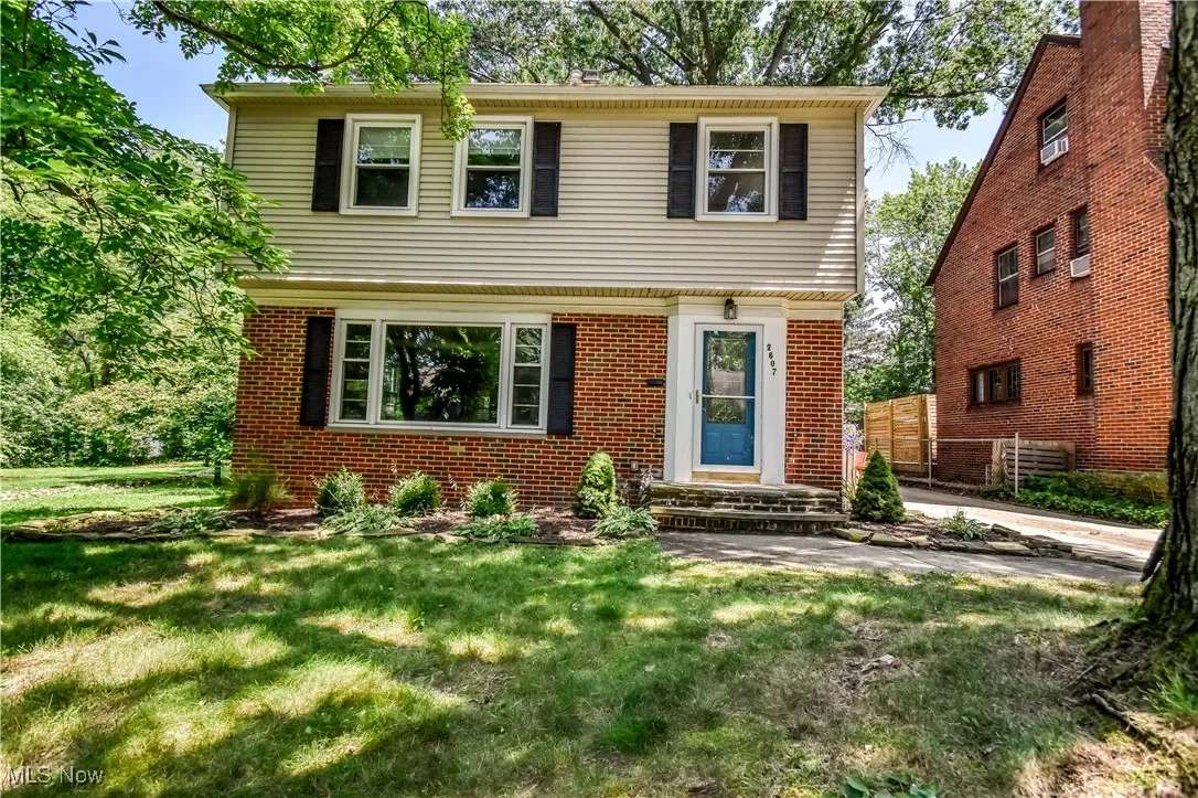 Colonial home featuring a front lawn and brick siding