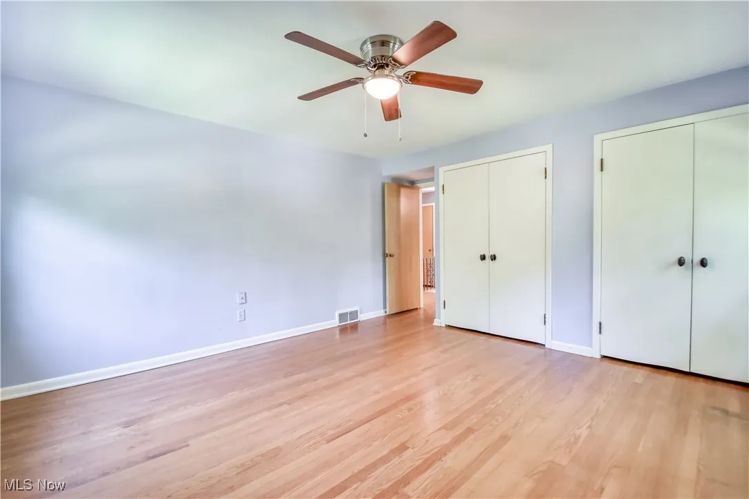 Unfurnished bedroom featuring two closets, light wood finished floors, and a ceiling fan