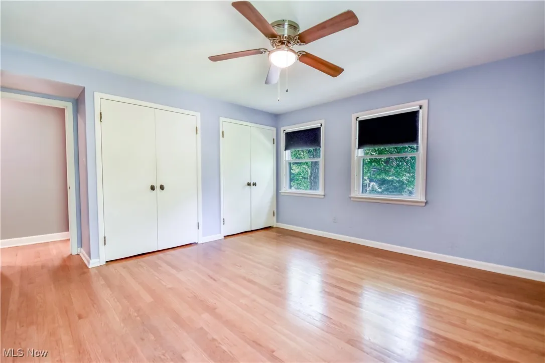 Unfurnished bedroom featuring two closets, wood finished floors, and ceiling fan