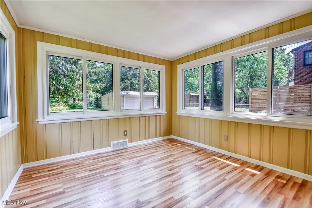 Unfurnished sunroom featuring wood finished floors, a wooden deck, and crown molding