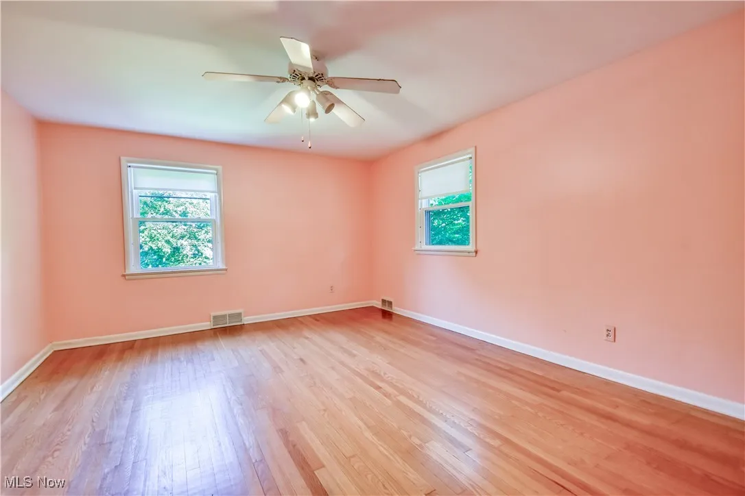 Spare room featuring healthy amount of natural light, light wood-type flooring, and a ceiling fan