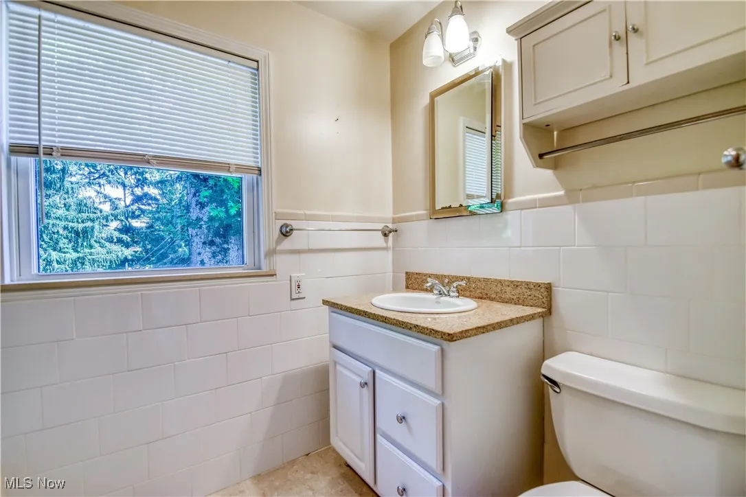 Bathroom featuring tile walls, vanity, and wainscoting