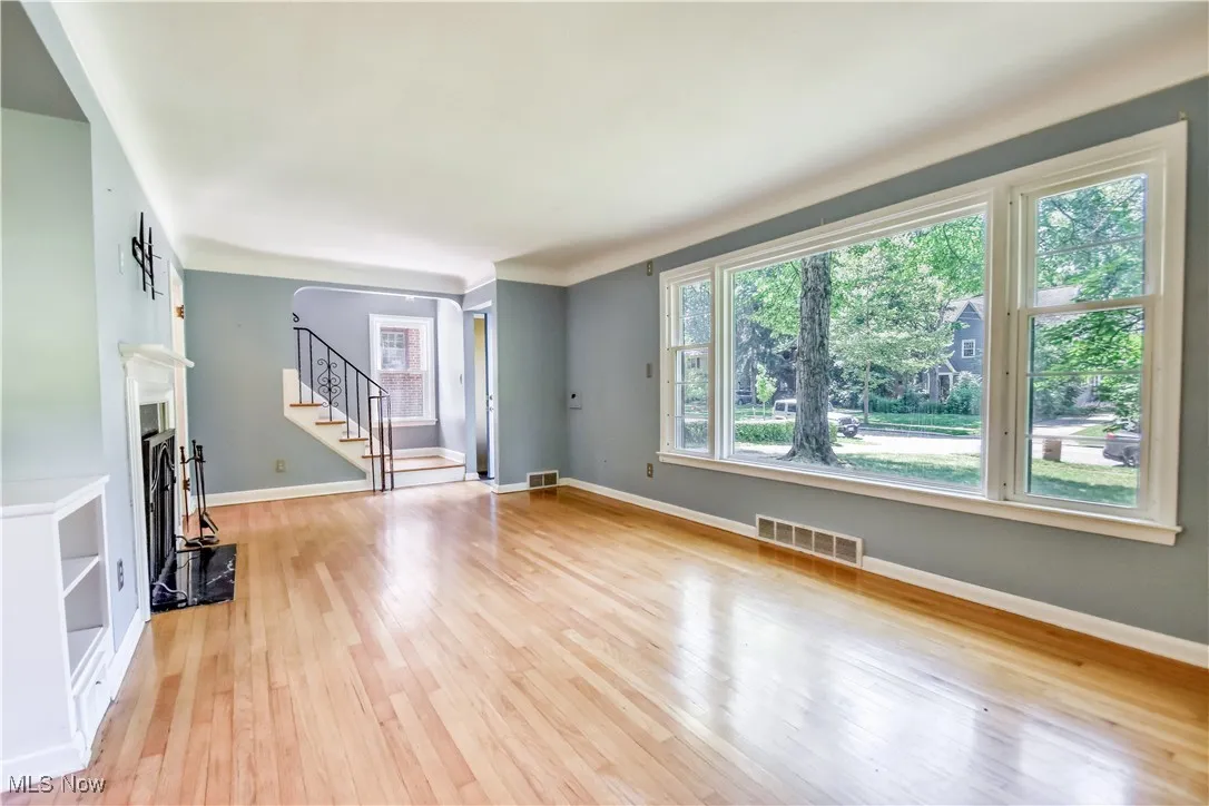 Unfurnished living room with light wood-type flooring and stairway