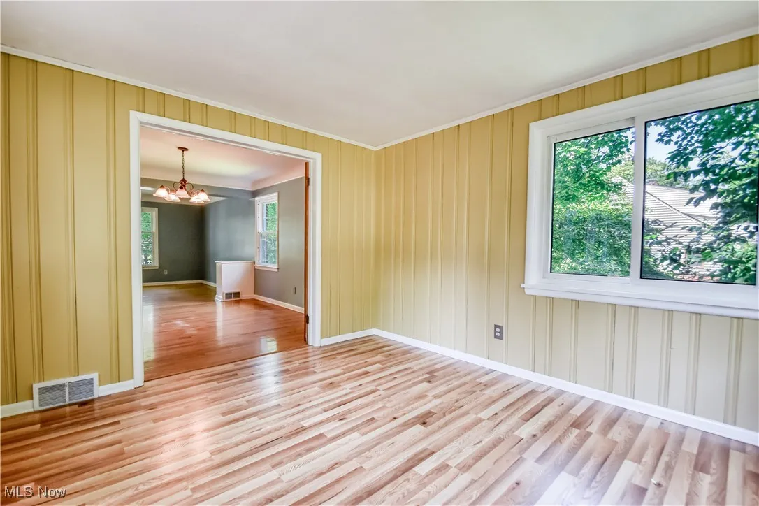 Spare room featuring ornamental molding, a chandelier, and light wood finished floors