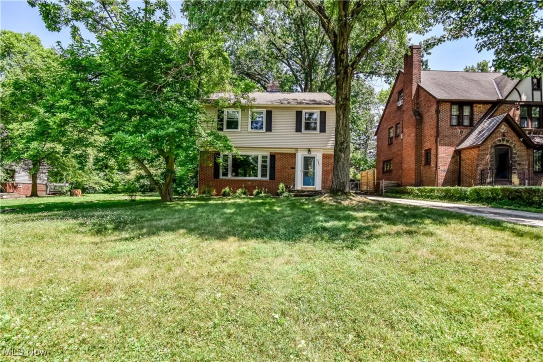 Colonial home with brick siding, a front lawn, and a chimney