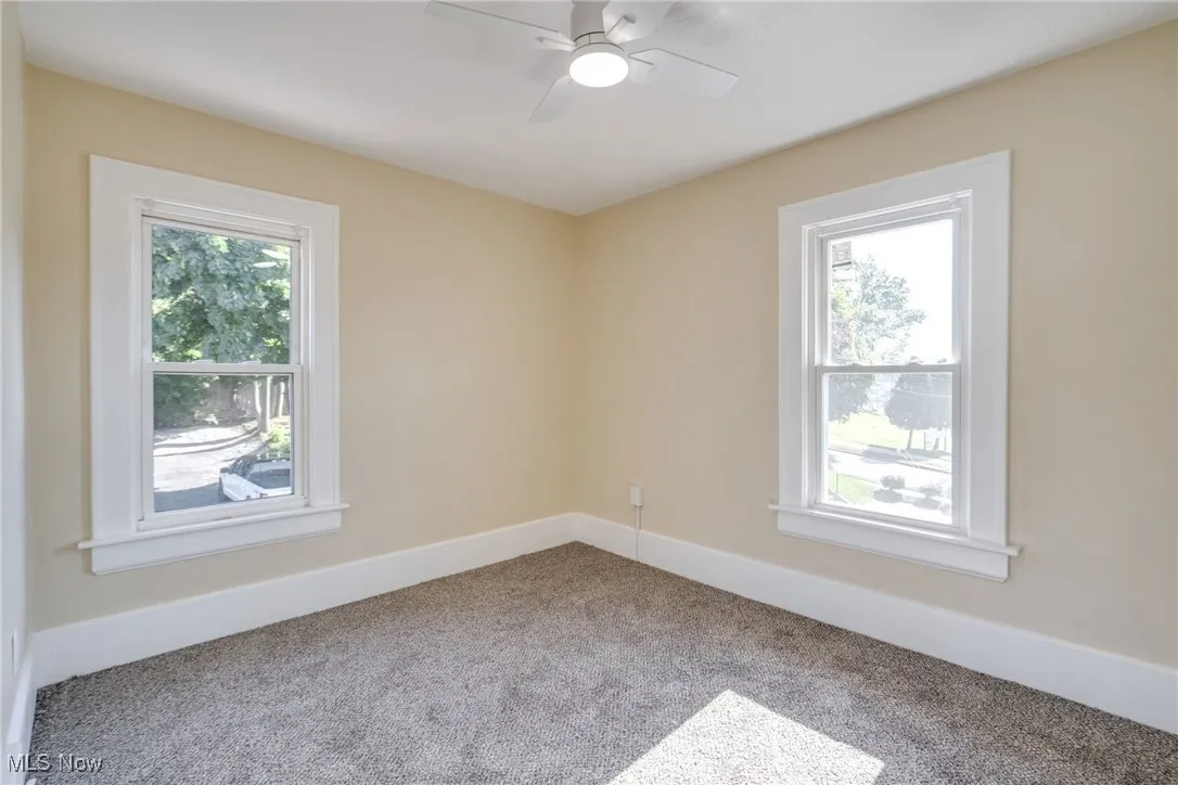 Carpeted empty room with baseboards and a ceiling fan