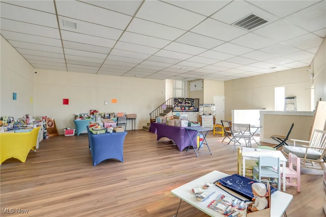 Rec room with wood finished floors and a paneled ceiling