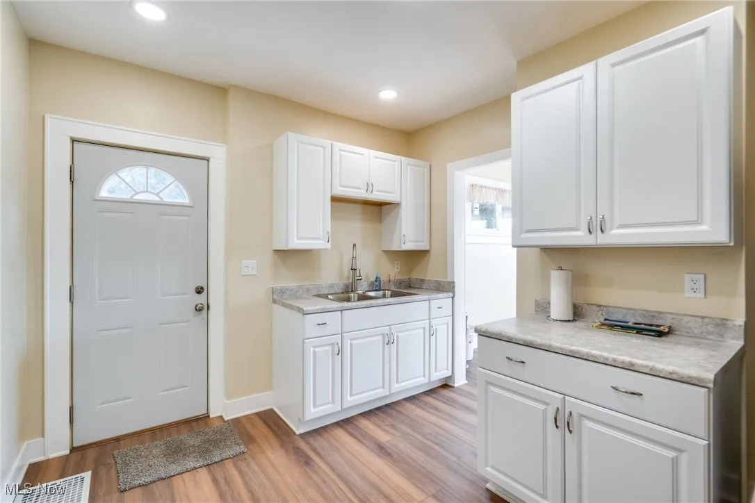Kitchen with light wood finished floors, white cabinetry, light countertops, and recessed lighting