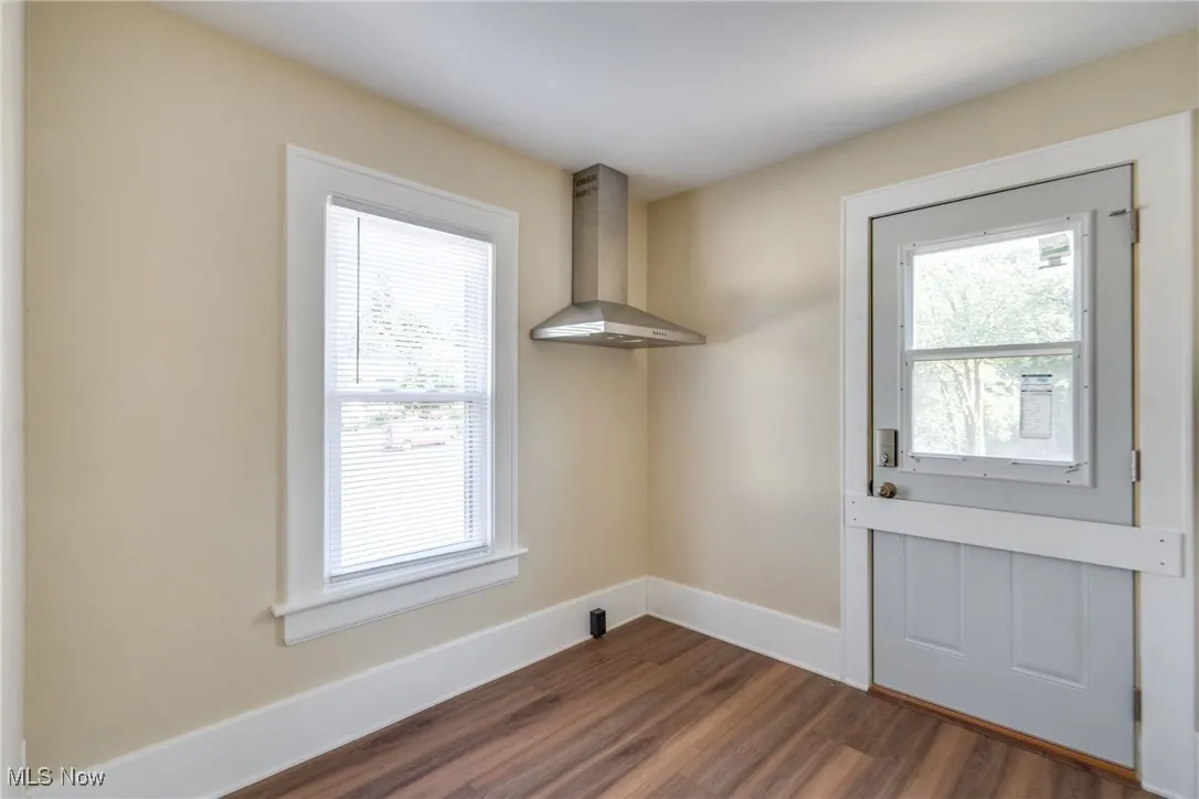 Unfurnished dining area with dark wood-style floors and baseboards