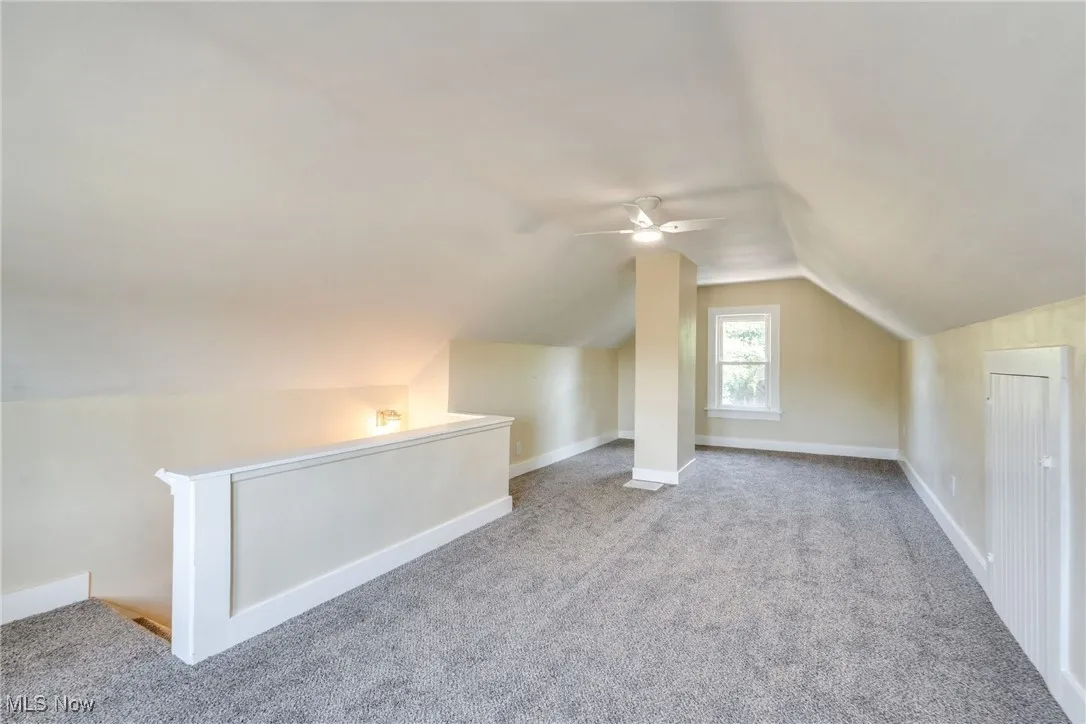 Additional living space featuring carpet, lofted ceiling, and a ceiling fan