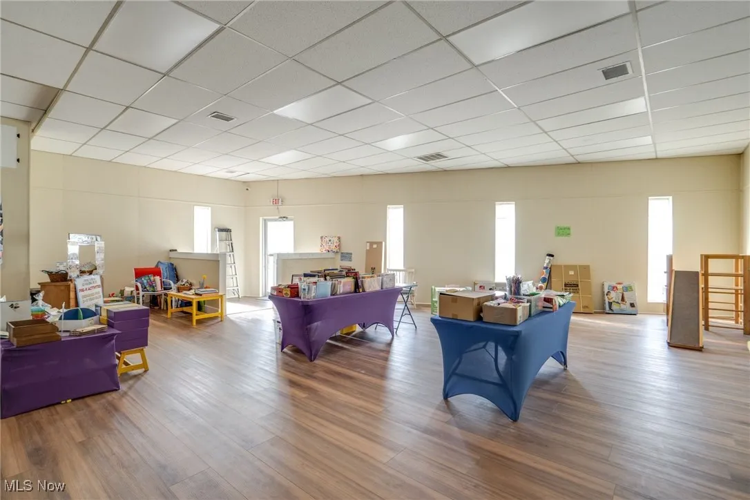Living room with plenty of natural light, a paneled ceiling, and wood finished floors