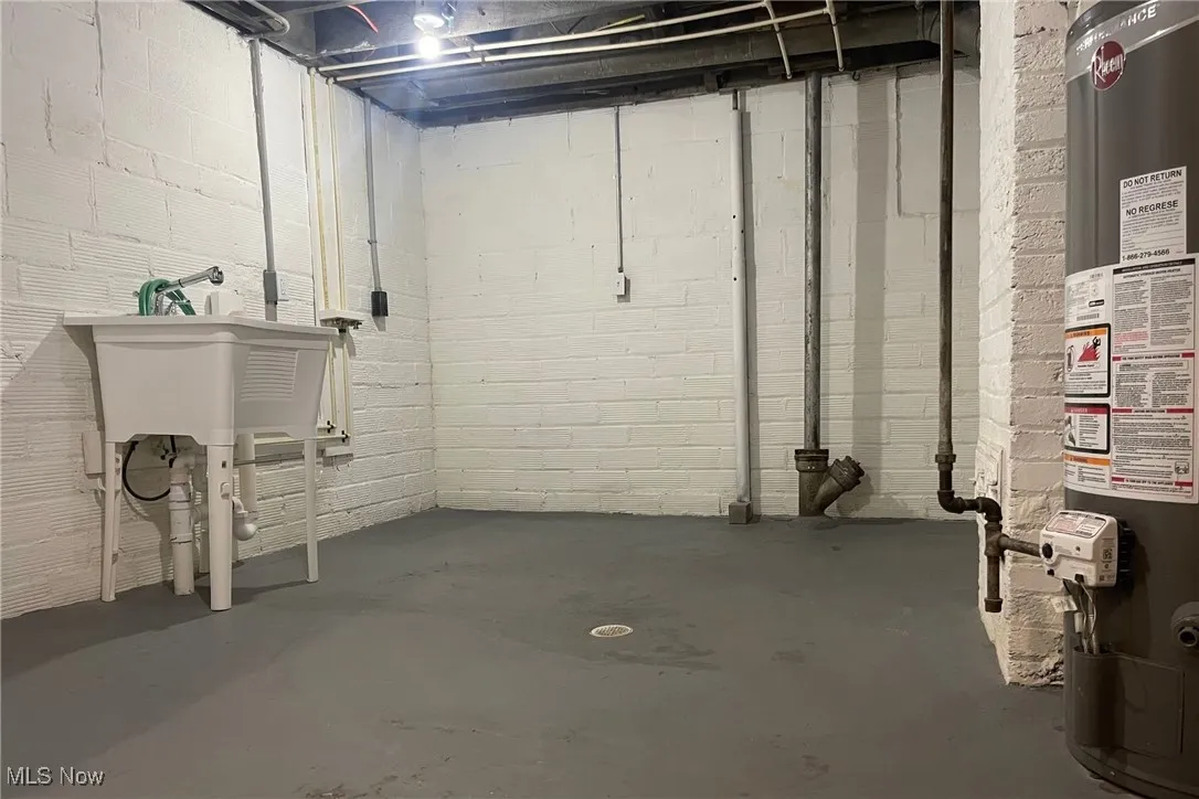 Unfinished below grade area with water heater and concrete block wall