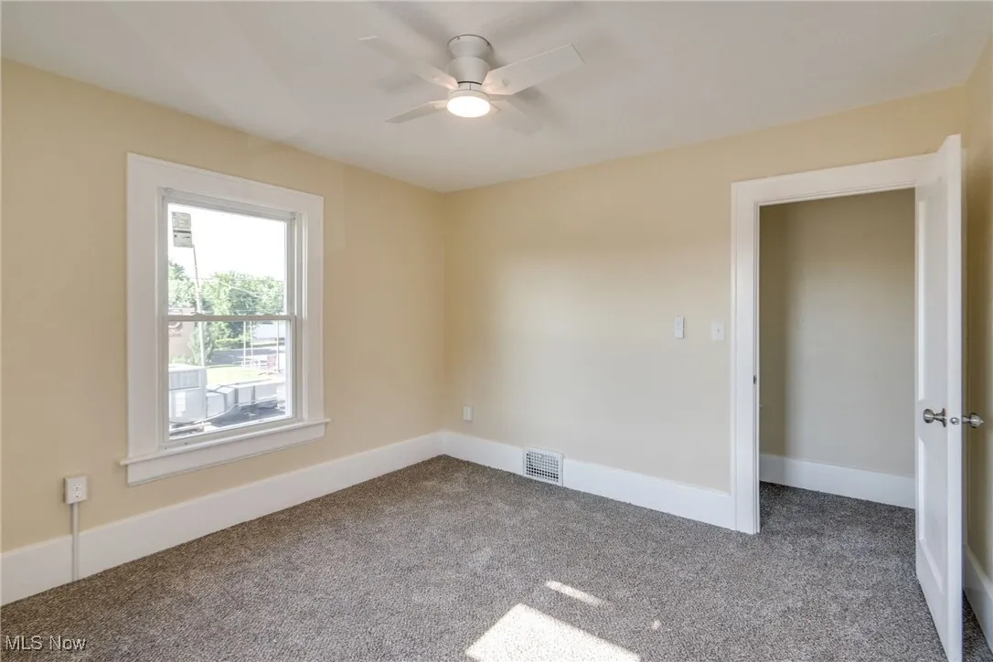 Carpeted empty room featuring ceiling fan and baseboards