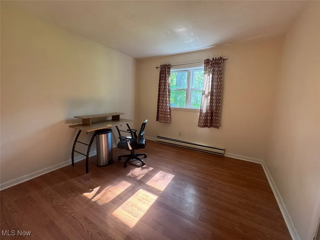 Bedroom featuring a baseboard heating unit and wood finished floors