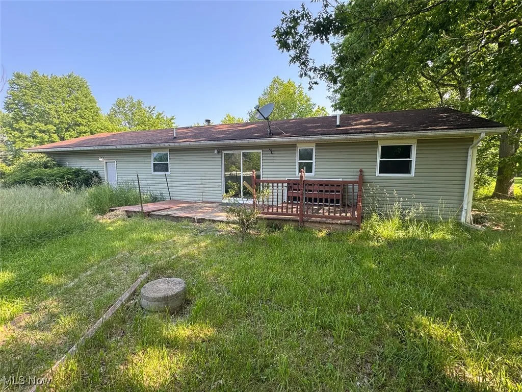 Back of property featuring a wooden deck and a yard