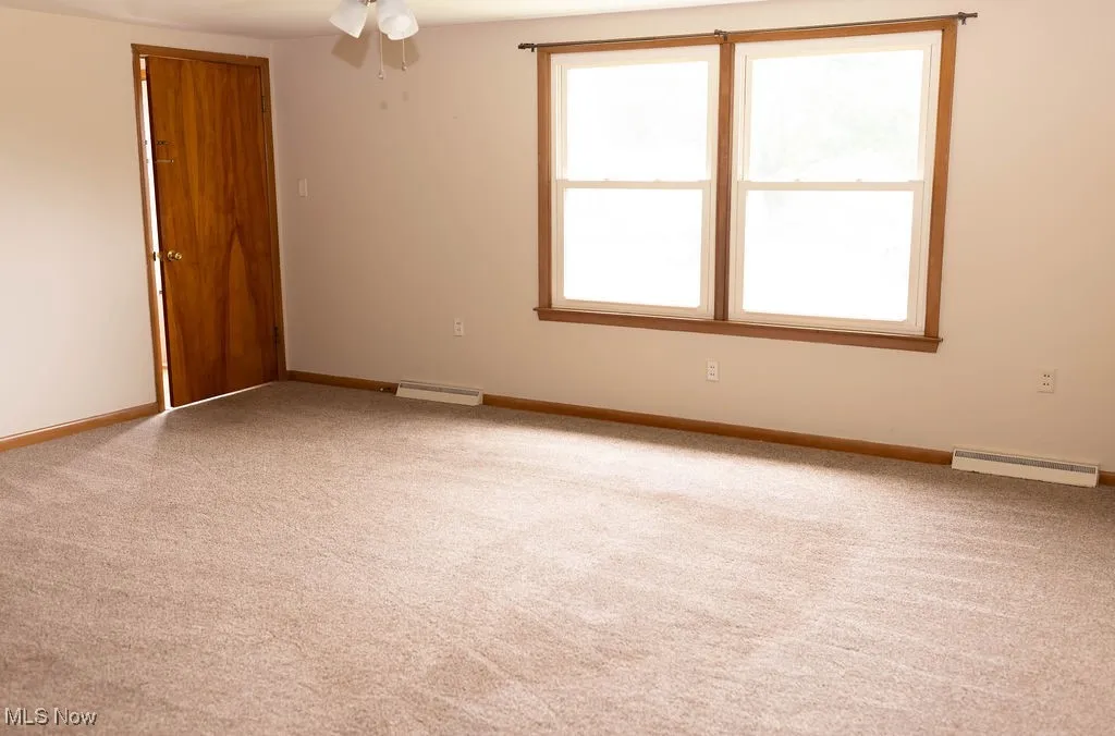 Unfurnished room featuring carpet flooring, baseboard heating, and a ceiling fan
