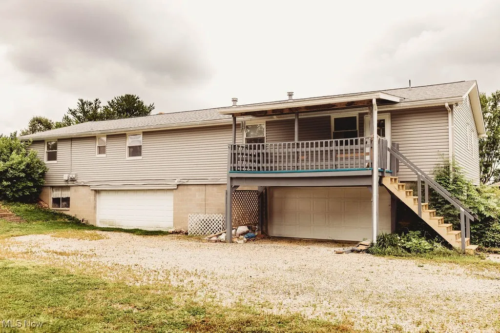 Rear view of house featuring a garage, driveway, stairway, and covered porch