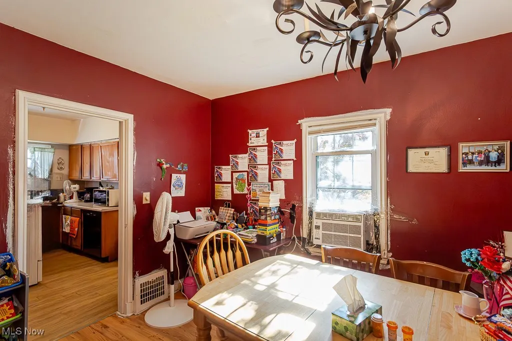 Dining area with a chandelier, cooling unit, and light wood-style floors