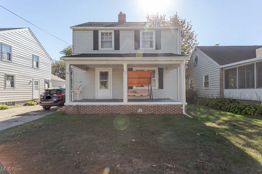View of front of home with covered porch, a chimney, and a front lawn