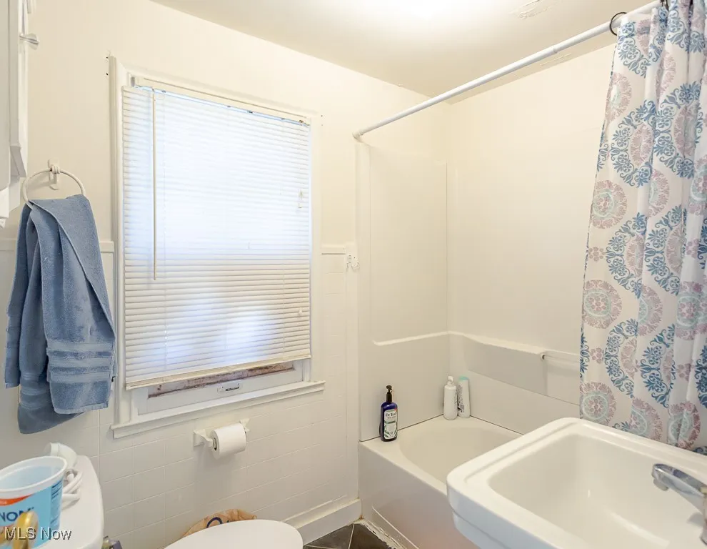 Full bathroom with toilet and shower / bath combo with shower curtain