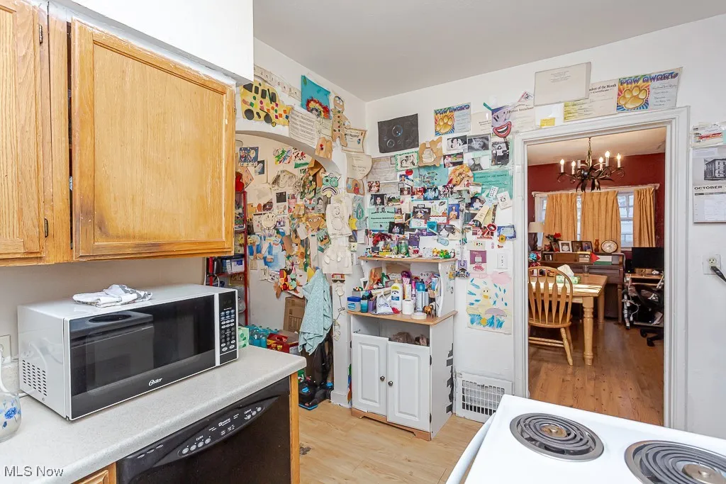 Kitchen featuring a chandelier, black dishwasher, light wood-style floors, light countertops, and range