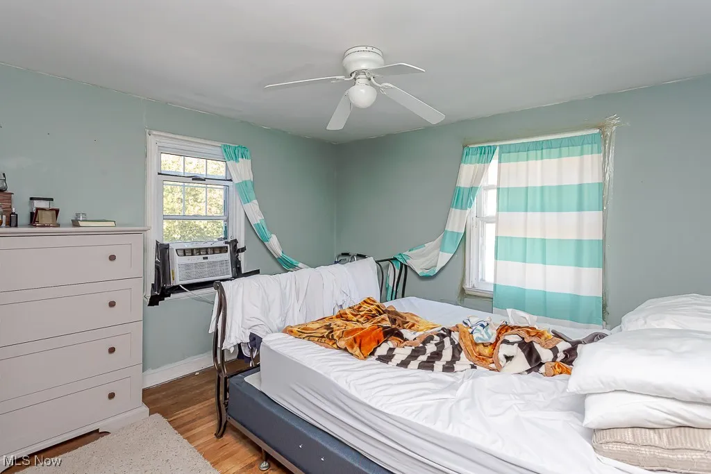Bedroom with wood finished floors, cooling unit, and ceiling fan