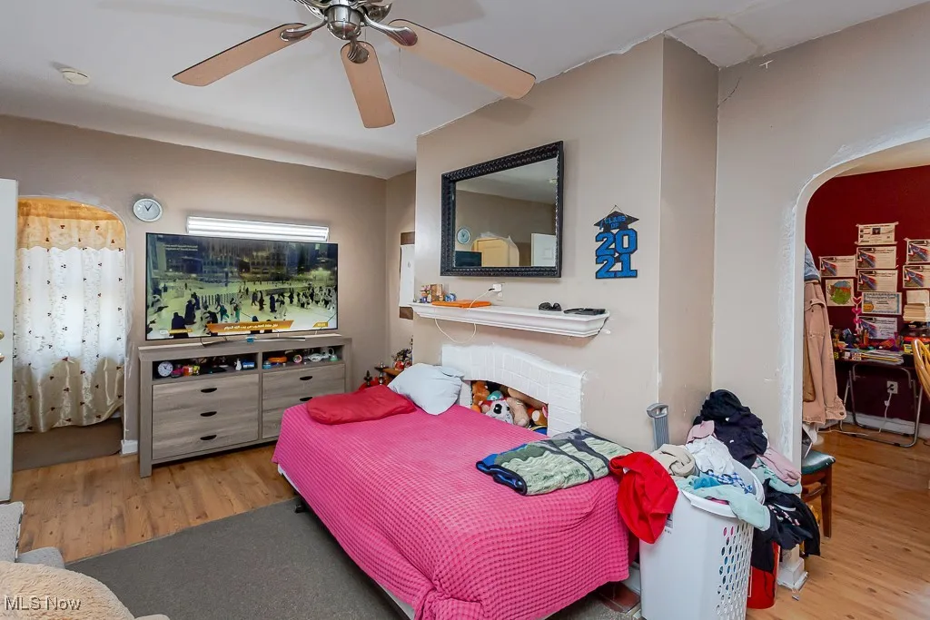 Bedroom featuring arched walkways, wood finished floors, and a ceiling fan