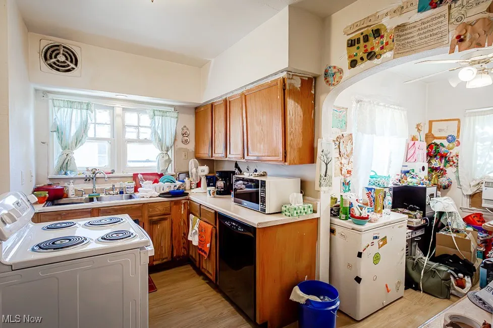 Kitchen featuring dishwasher, electric stove, light wood-type flooring, brown cabinetry, and light countertops