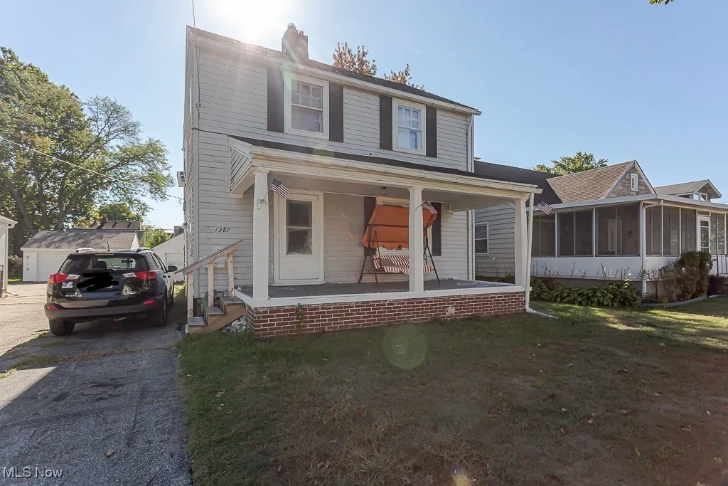 View of front facade featuring a porch, a sunroom, a front lawn, and a chimney