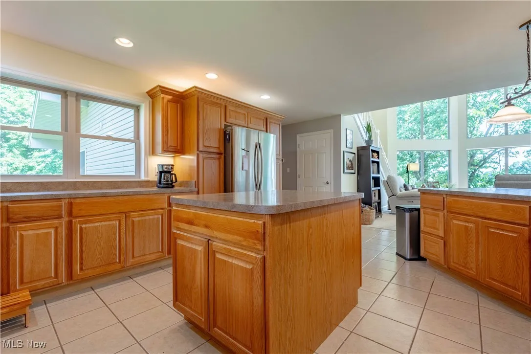 Kitchen with freestanding refrigerator, a kitchen island, plenty of natural light, light tile patterned floors, and recessed lighting