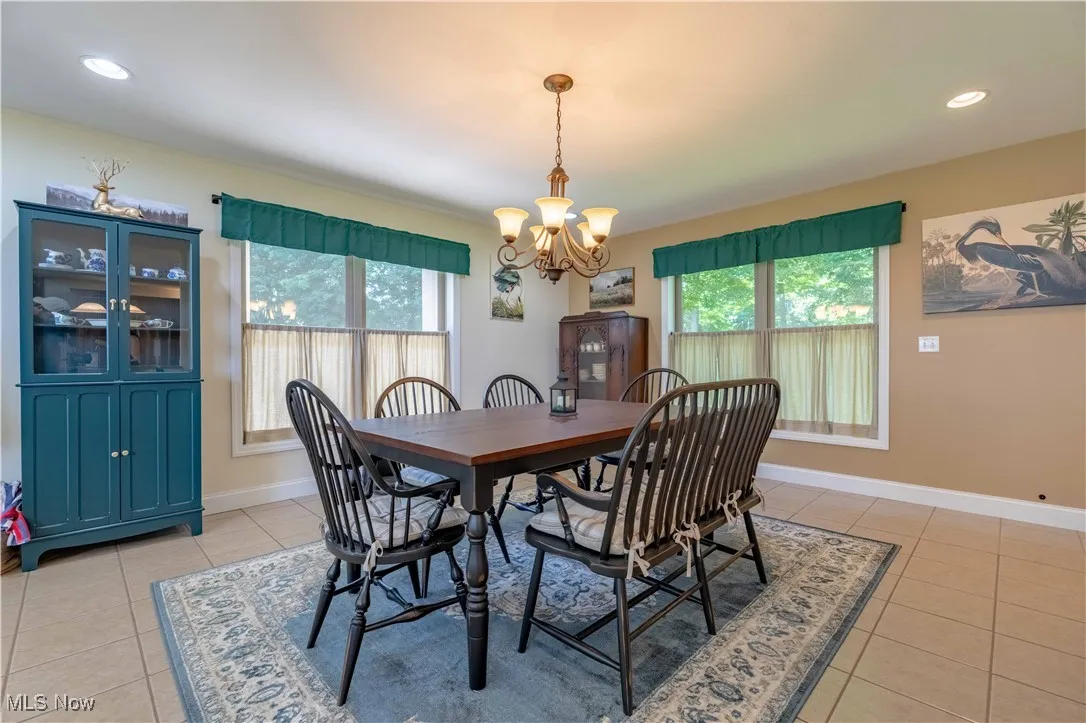 Dining area with light tile patterned flooring, healthy amount of natural light, a chandelier, and recessed lighting