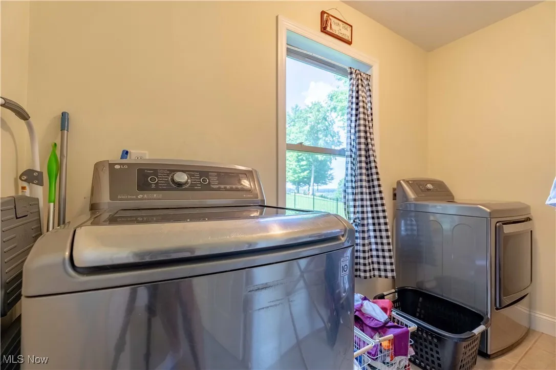 Laundry room with washing machine and clothes dryer, healthy amount of natural light, and tile patterned floors