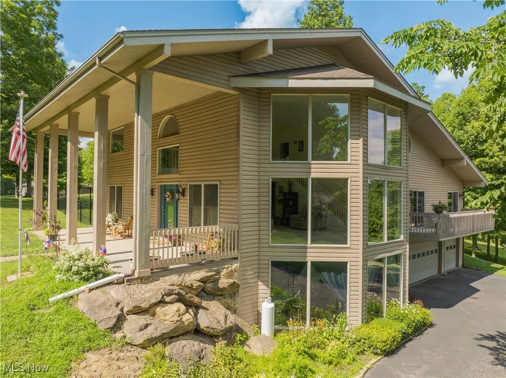View of side of home featuring an attached garage, driveway, and a porch