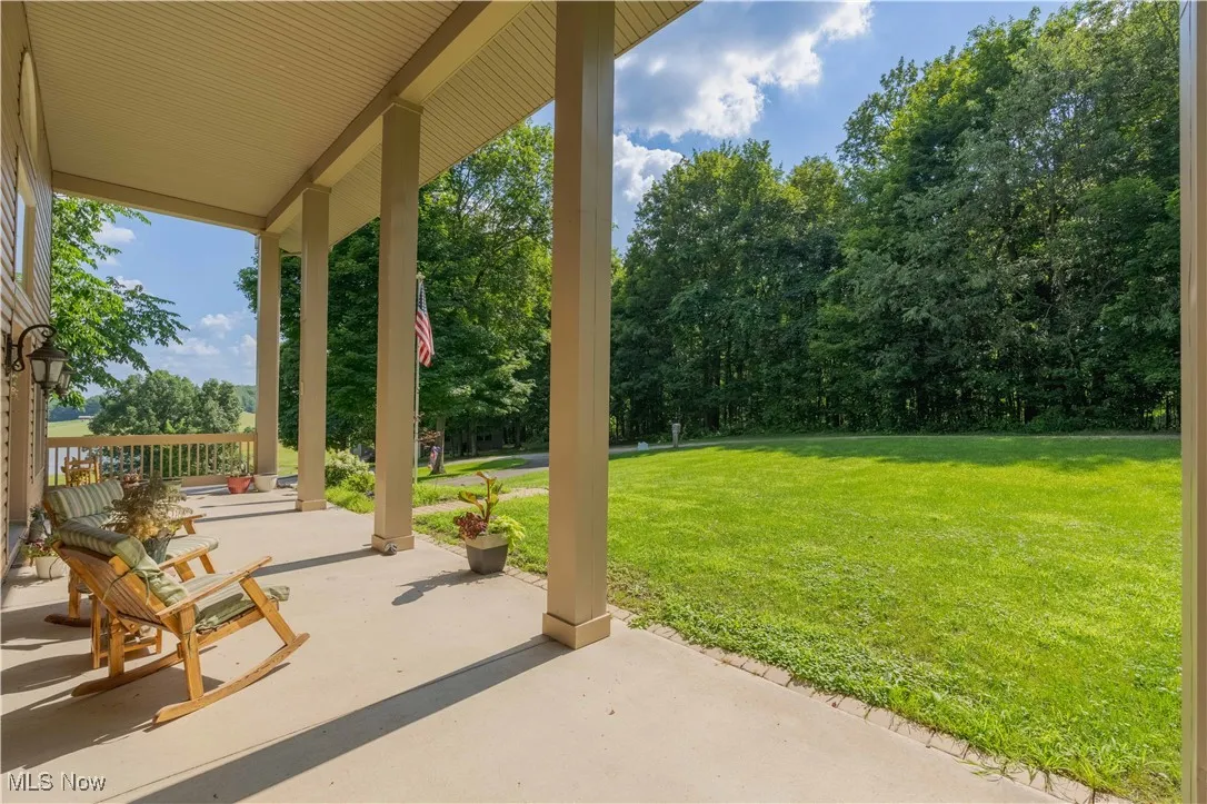 Porch with a yard and view of wooded area