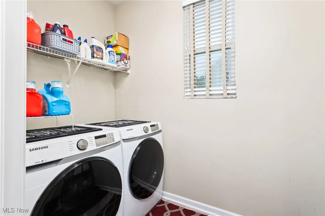 Washroom featuring independent washer and dryer and baseboards