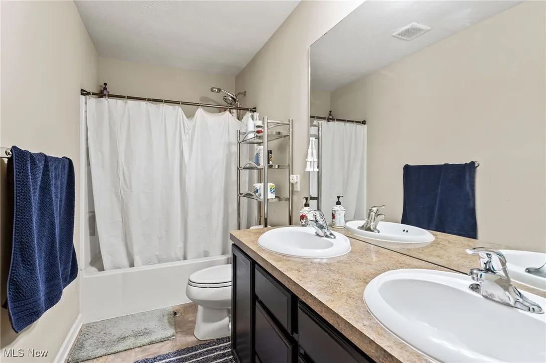Full bath featuring shower / bath combo and double vanity