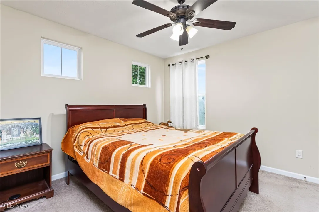 Bedroom with light colored carpet and a ceiling fan