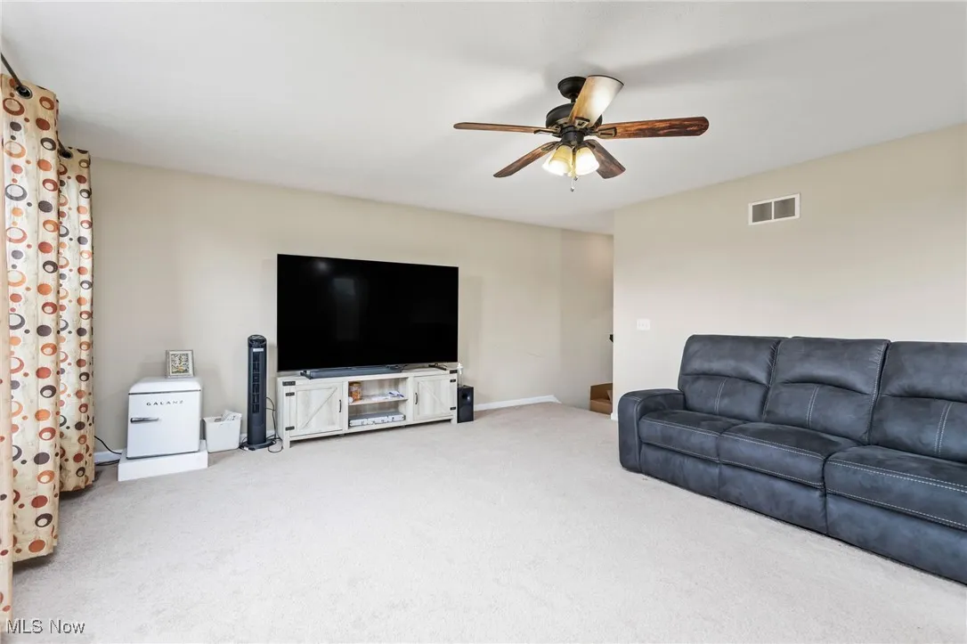 Living area featuring ceiling fan and carpet flooring