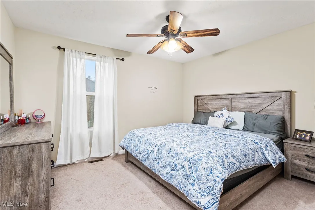 Carpeted bedroom with a ceiling fan