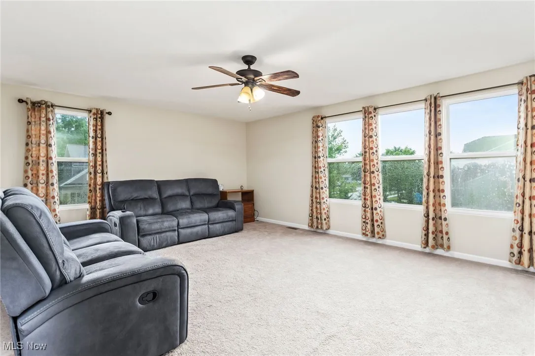 Carpeted living room with a ceiling fan and healthy amount of natural light