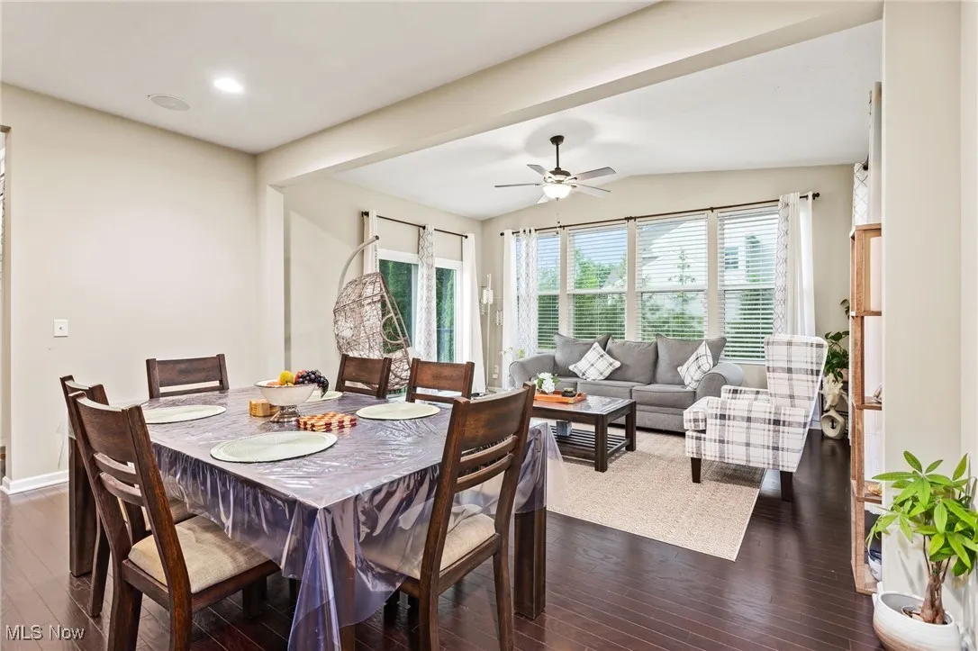 Dining area featuring dark wood-style floors, vaulted ceiling, and a ceiling fan