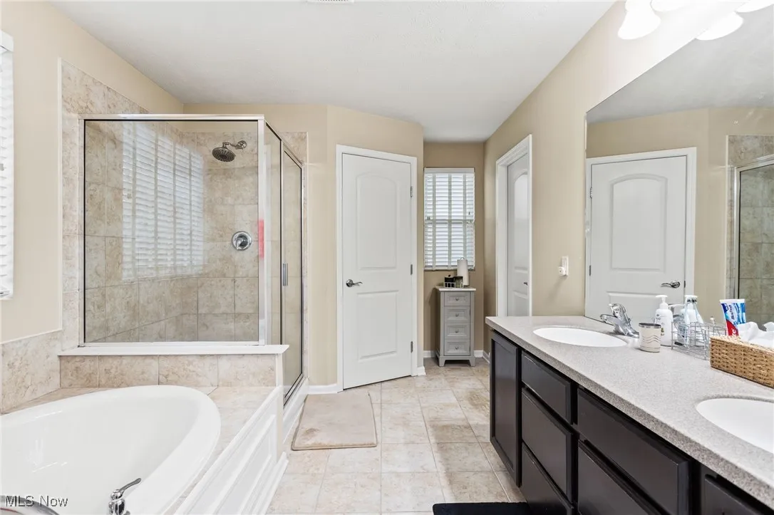 Full bathroom with a shower stall, a bath, and double vanity